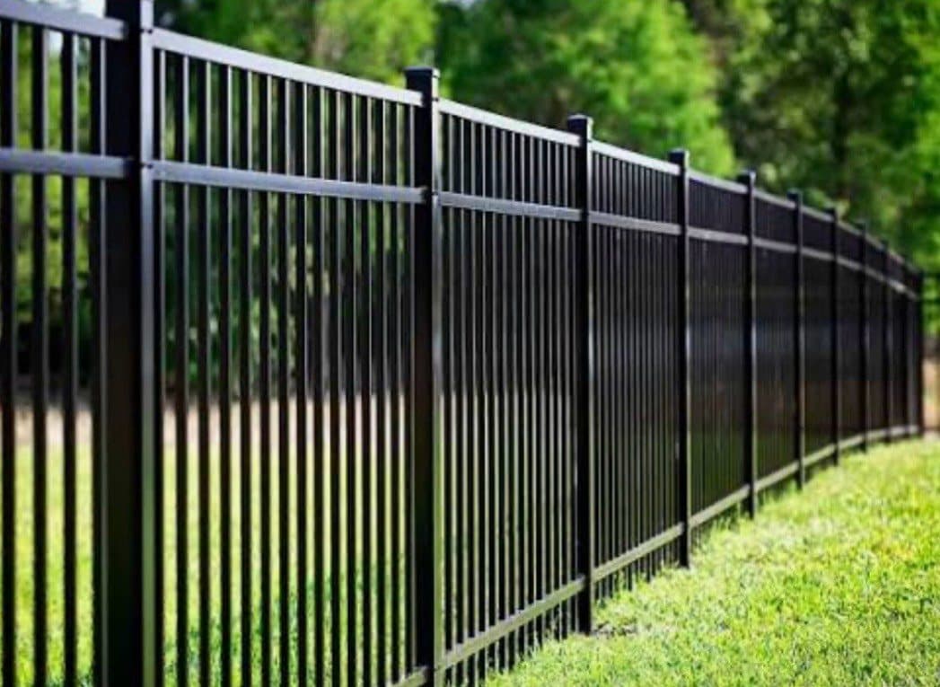 Black aluminum fence along a green lawn