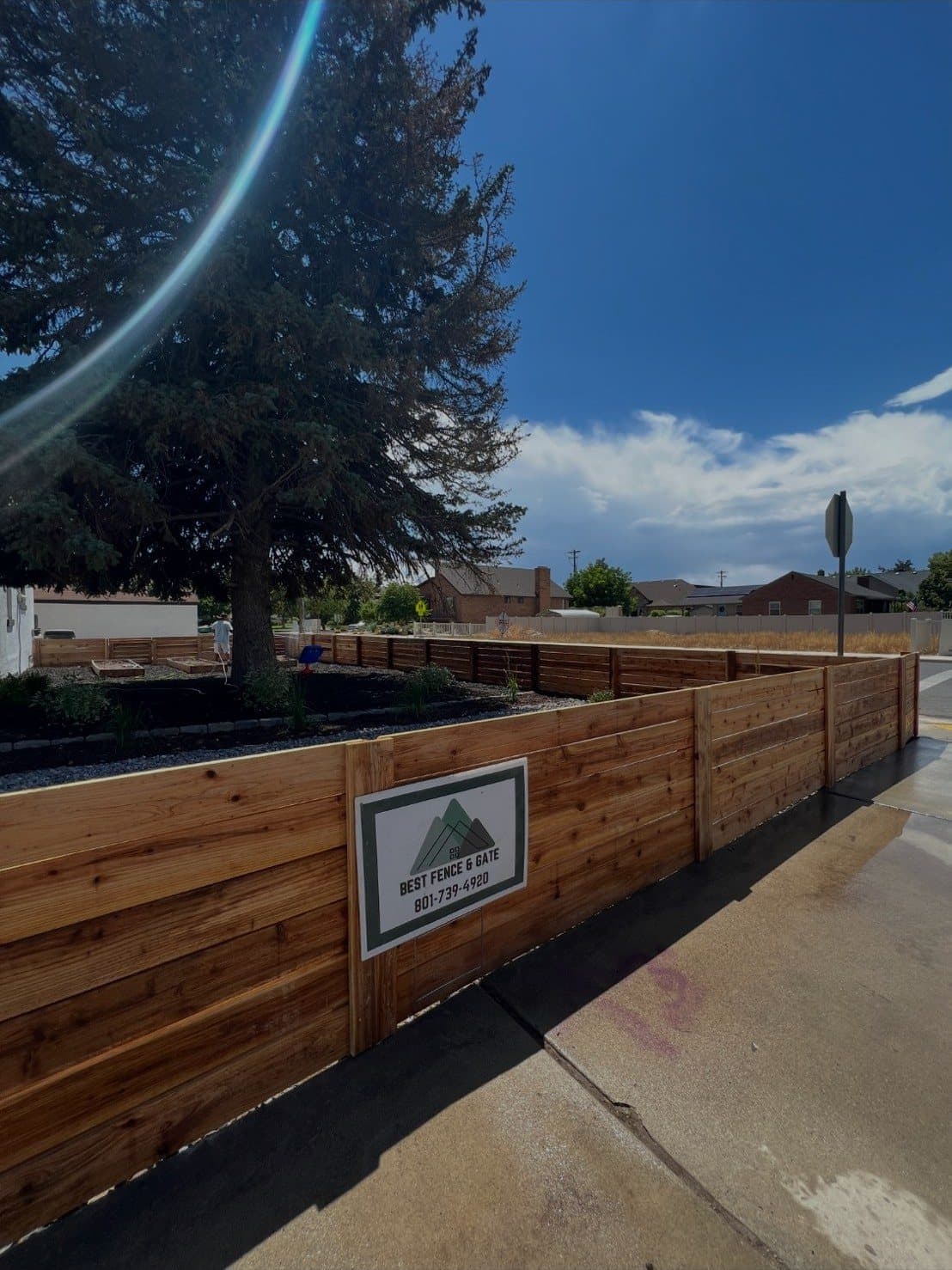 Horizontal cedar fence along a sidewalk with a Best Fence & Gate sign