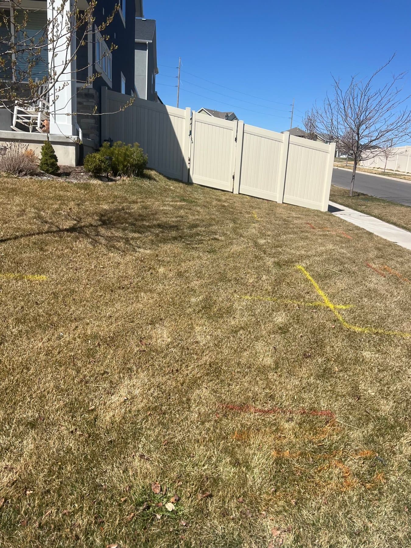 Tan vinyl privacy fence and gate along a corner lot