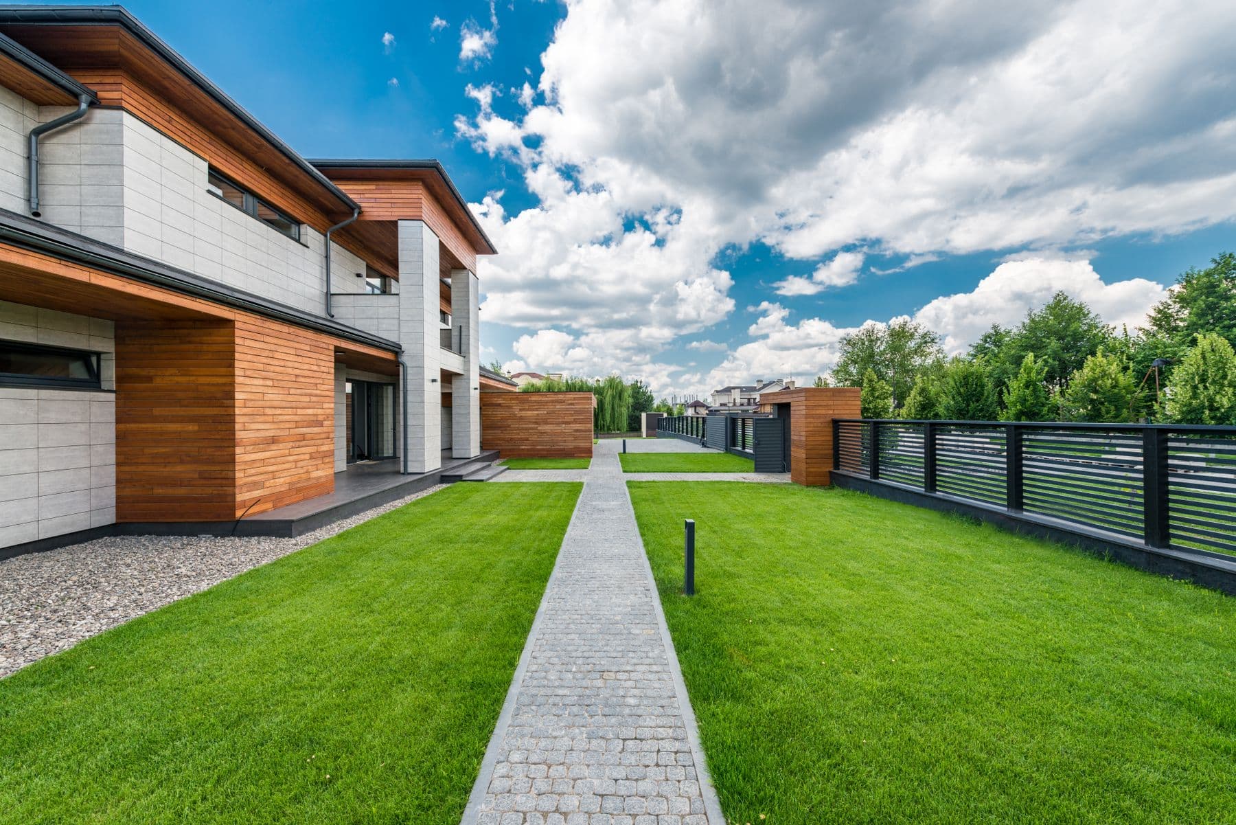 Modern luxury home with a black horizontal slat fence along the lawn