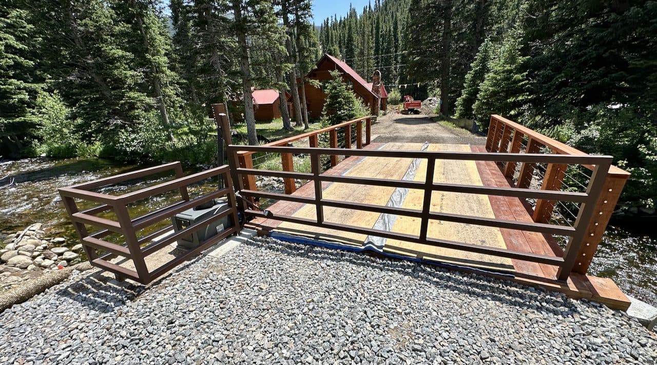 Rustic steel LazyGate at a mountain cabin bridge