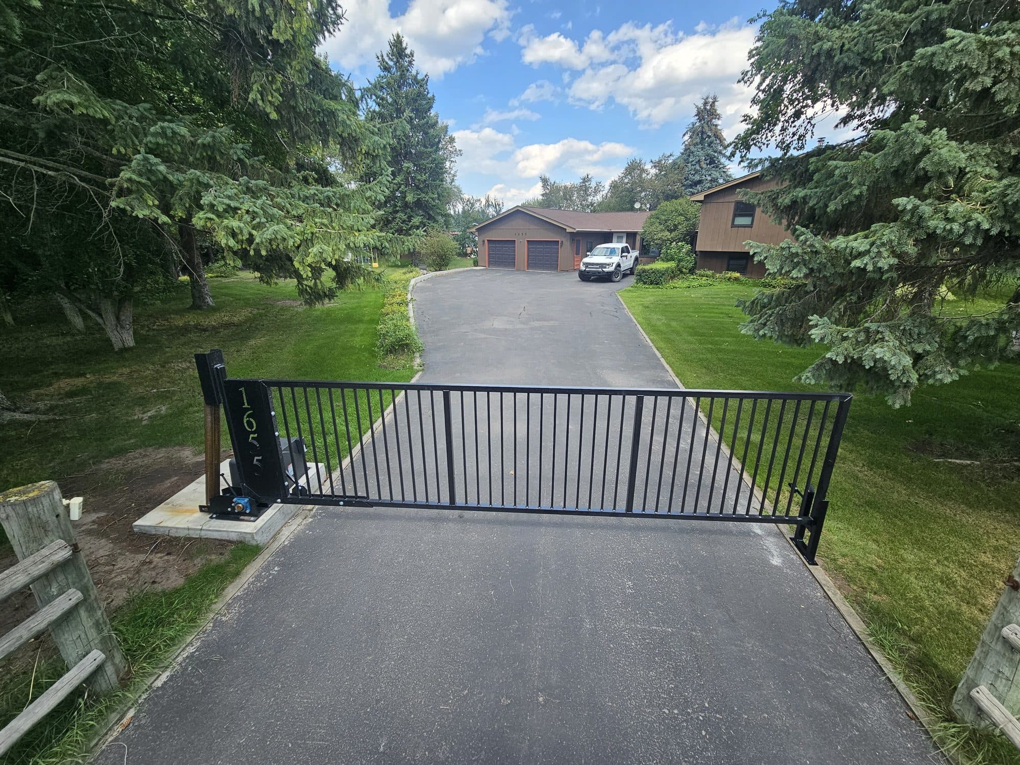 LazyGate vertical pivot gate across a tree-lined driveway
