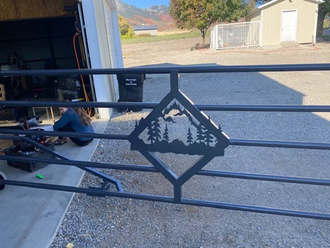 Gate panel with a laser-cut elk and mountain scene