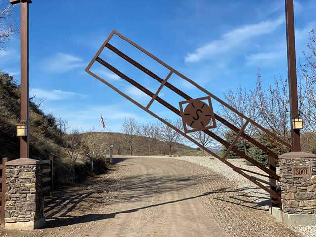 Ranch gate with a laser-cut monogram between stone pillars