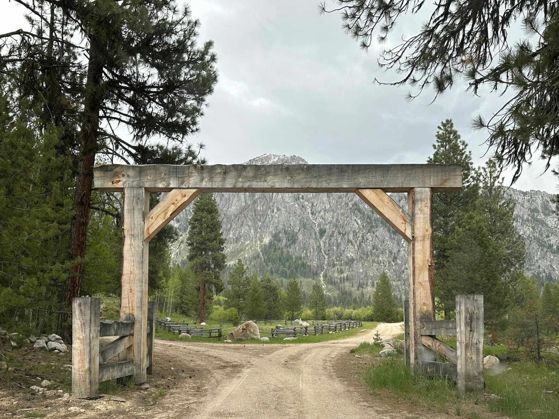 Timber ranch entry arch with mountains in the background
